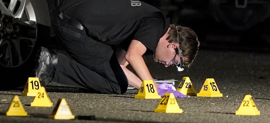 A Washington State Patrol Crime Lab worker looks at evidence markers in the early morning hours of Friday, Sept. 4, in Lacey, Wash. at the scene where Michael Reinoehl was killed.
