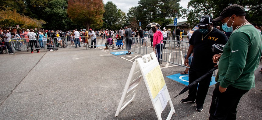 Two men look at a sign containing voting information on Monday, Oct. 12, in Marietta, Georgia during early voting.