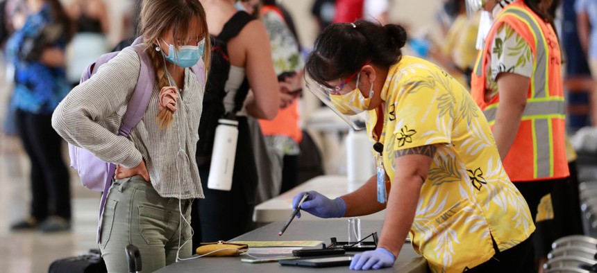 A traveler is assisted by a state official at the Daniel K. Inouye International Airport Thursday, Oct. 15, 2020, in Honolulu. 