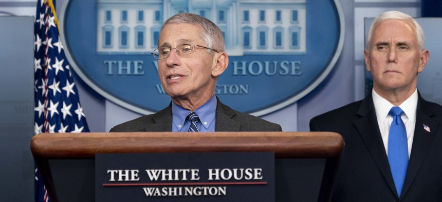 Fauci speaks at the White House in April as Mike Pence looks on.