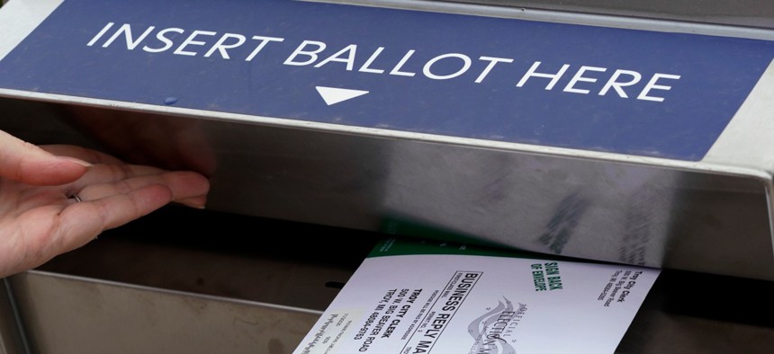 Nikki Schueller inserts her absentee voter ballot into a drop box, Thursday, Oct. 15, 2020, in Troy, Mich.