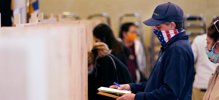 Bruce Lowell looks down at his ballot as he enters a voting booth at an early voting location. 