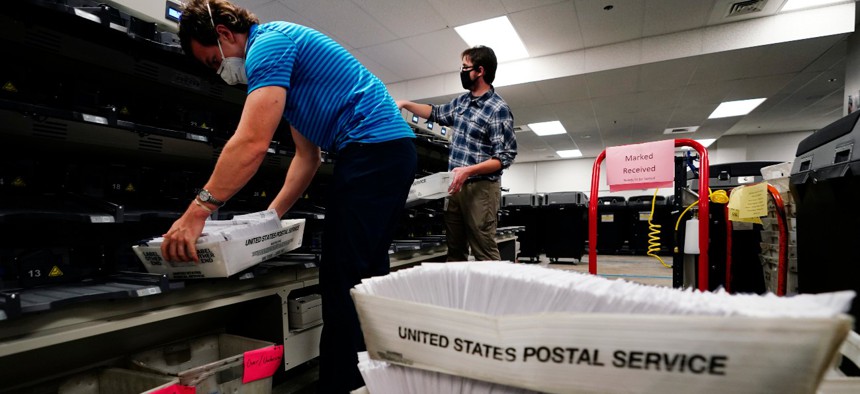 Kyle Hallman, left, and Michael Imms, with Chester County Voter Services, gather mail-in ballots being sorted for the general election in West Chester, Pa.