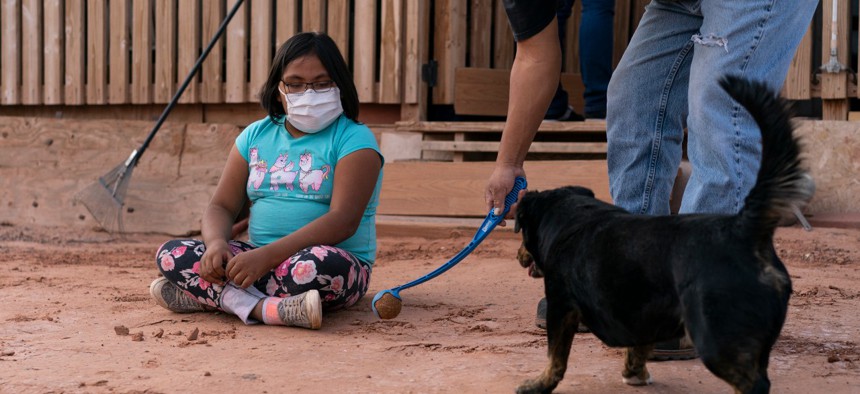 A girl watches her father play ball with their dog in April on a Navajo reservation in Tuba City, Arizona. Navajo Nation leaders say the Census Bureau did not spend enough time counting residents to avoid an undercount, a complaint echoed in Louisiana.