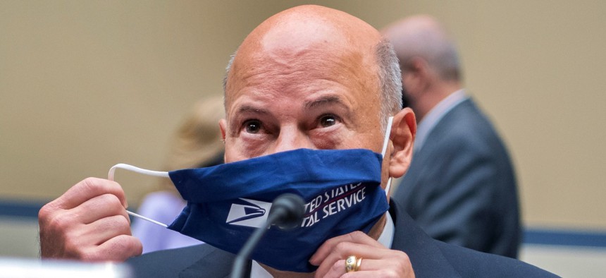 Postmaster General Louis DeJoy removes his face mask as he arrives to testify before a House Oversight and Reform Committee hearing on the Postal Service in August. 