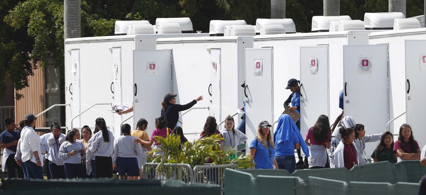 Migrant children stand outside portable restrooms at the Homestead Temporary Shelter for Unaccompanied Children, Monday, May 6, 2019, in Homestead, Fla.