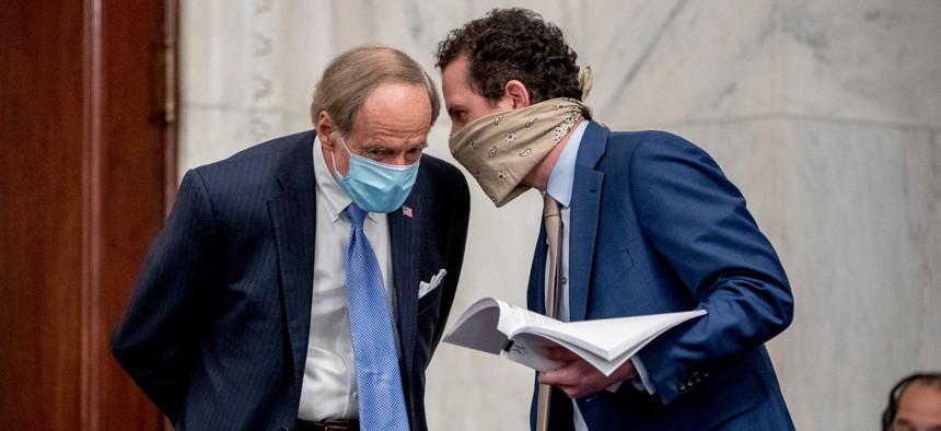 Sen. Tom Carper, D-Del., left, speaks to an aide on Capitol Hill in May. Carper is one of several Democrats keeping an eye on Trump administration efforts to reclassify federal jobs into at-will positions.
