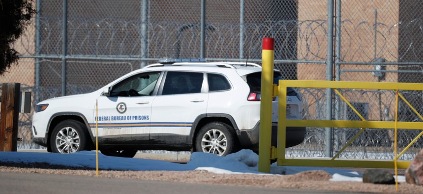 A guard guides a vehicle along the fenceline around the federal correctional institution in Englewood, Colo. 