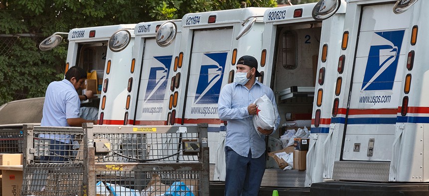 Postal workers load packages in their mail delivery vehicles in Los Angeles in August. 