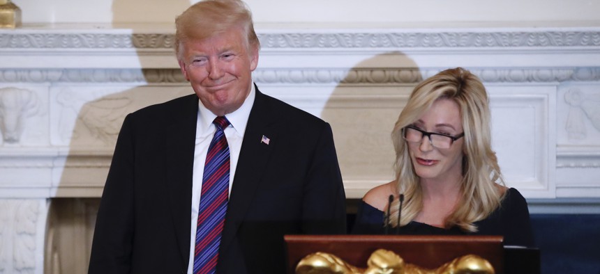 President Donald Trump smiles as pastor Paula White prepares to lead the room in prayer, during a dinner for evangelical leaders in the State Dining Room of the White House in 2018.