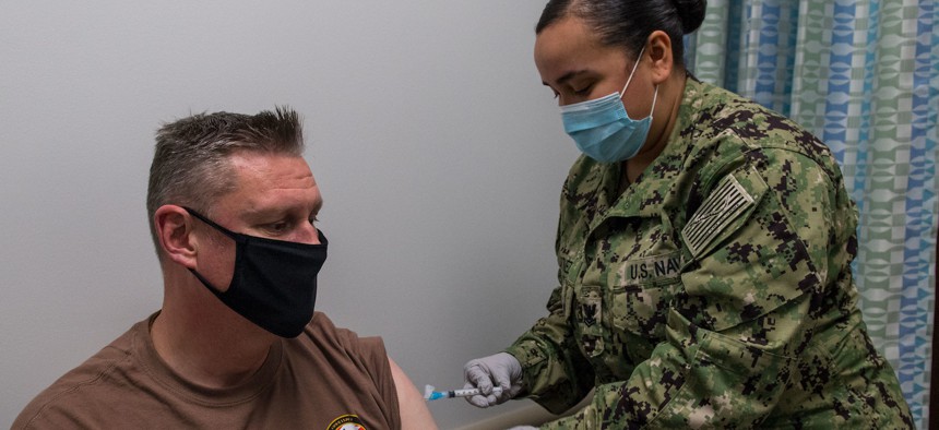  Fleet Master Chief Spike Call, left, Command Master Chief of U.S. 5th Fleet, receives a COVID-19 vaccine from Hospital Corpsman 2nd Class Rose Martinez onboard Naval Support Activity Bahrain, Jan. 4. 