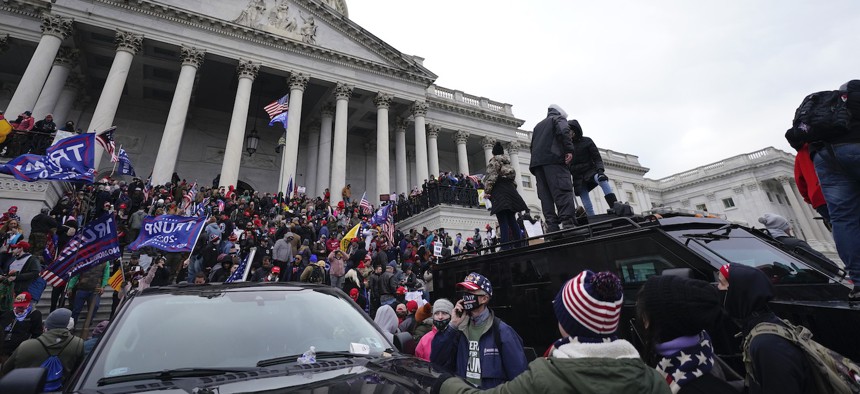 Trump supporters stand on top of a police vehicle