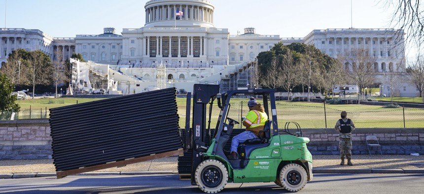 DC National Guard stands outside a mostly quiet Capitol, Thursday morning, Jan. 7, 2021 in Washington, as workers place security fencing in place. 