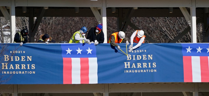 Workers put up bunting on a press riser for the upcoming inauguration of President-Elect Biden and Vice President-Elect Kamala Harris, on Pennsylvania Avenue in front of the White House. 