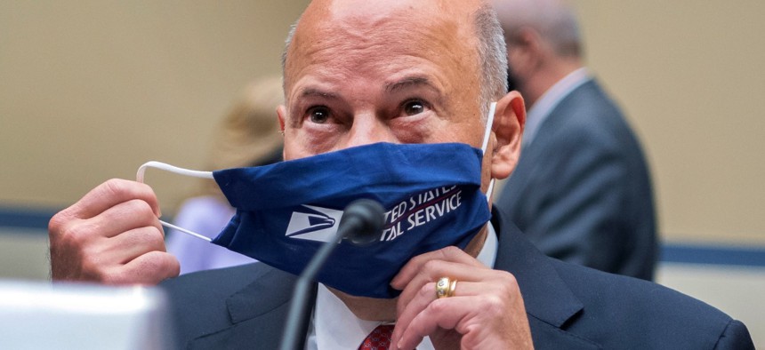 Postmaster General Louis DeJoy removes his face mask as he testifies before Congress last August.