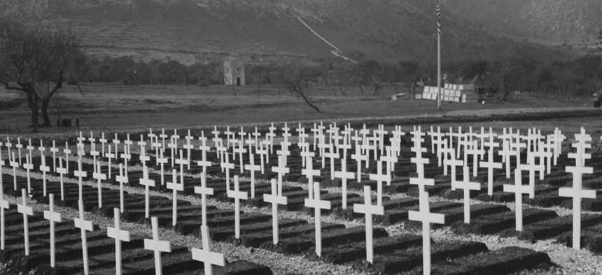 Graves of American war dead mark the mountain valley floor an officers and men of all arms of the service form for Armistice day ceremonies at the military cemetery in Palermo, Sicily