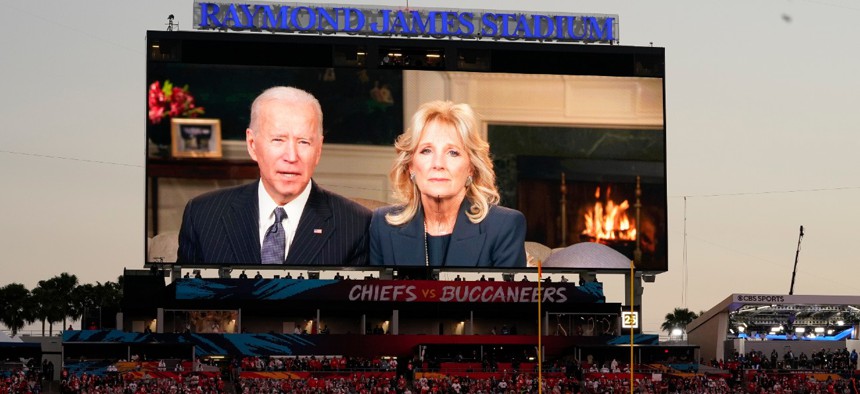 Fans watch a broadcast of President Biden and First Lady Jill Biden before the NFL Super Bowl 55 football game between the Kansas City Chiefs and Tampa Bay Buccaneers on Sunday. 