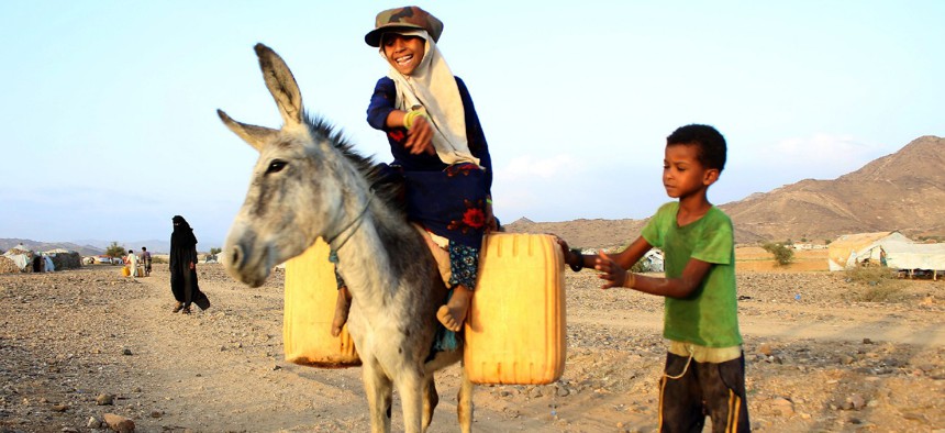 A girl rides a donkey carrying jerry cans filled with water from a cistern at a make-shift camp for displaced Yemenis in a severe shortage of water, in the northern Hajjah province on March 24, 2020. 