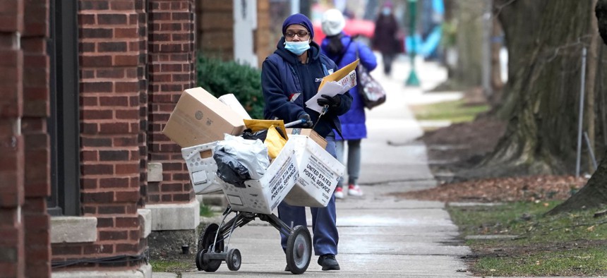 A U.S. postal worker delivers packages, boxes and letters on Dec. 22, 2020, along her route in the Hyde Park neighborhood of Chicago.