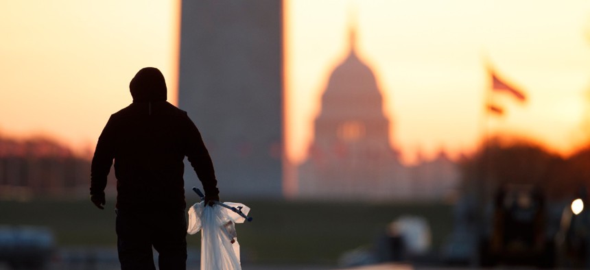 A National Park Service worker picks up trash along the drained Lincoln Memorial Reflecting Pool as the Washington Monument and the U.S. Capitol are seen in the distance in Washington, at sunrise. 