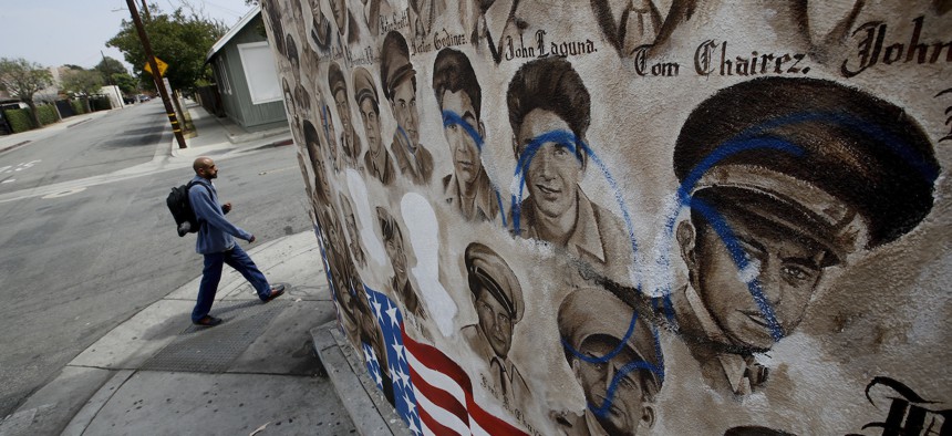 A person walks by a mural that features nearly 200 portraits of Mexican-American men and women who have served in World War II, the Korean War and the Vietnam War Tuesday, May 29, 2018, in Santa Ana, Calif. 