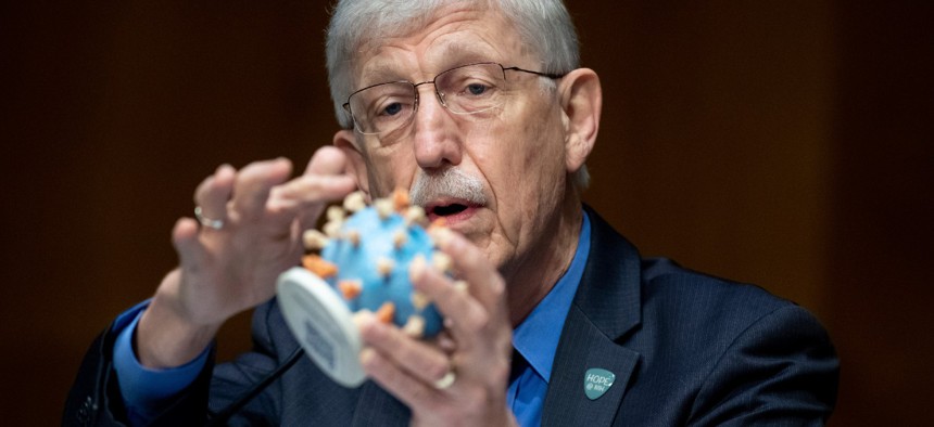 Dr. Francis Collins, director of the National Institutes of Health, holds up a model of COVID-19, known as coronavirus, during a Senate hearing in July. 