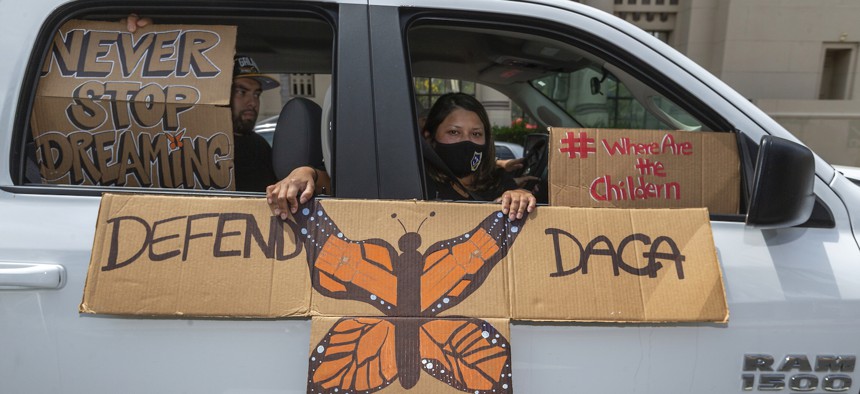 People hold signs during a vehicle caravan rally to support the Deferred Action for Childhood Arrivals Program (DACA), around MacArthur Park in Los Angeles in June 2020.
