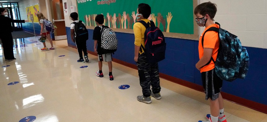 Students keep a social distance as they walk to their classroom at Oak Terrace Elementary School in Highwood, Ill. The Education Department is receiving $170 billion from the American Rescue Plan. 