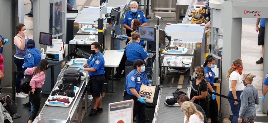 Transportation Security Administration agents process passengers at Denver International Airport in Denver in June 2020.