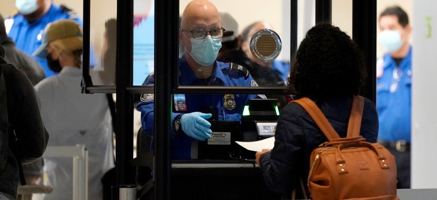 A TSA agent assist a traveler at a security checkpoint at Love Field Airport in Dallas. There were fewer air travelers in the United States last year, but a higher percentage of them were carrying guns.