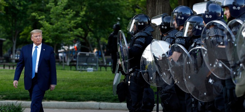 President Trump walks past police in Lafayette Park after he visited outside St. John's Church across from the White House Monday, June 1, 2020, in Washington.