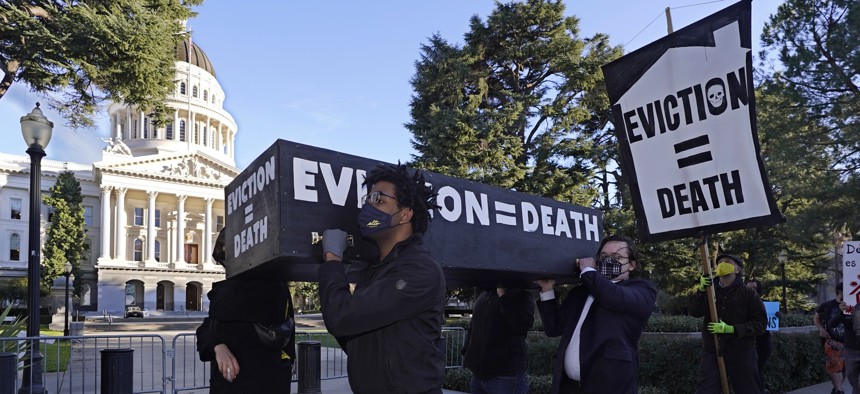 Demonstrators calling for lawmakers and Gov. Gavin Newsom to pass rent forgiveness and stronger eviction protections legislation, carry a mock casket past the Capitol in Sacramento, Calif., on Monday, Jan. 25, 2021. 
