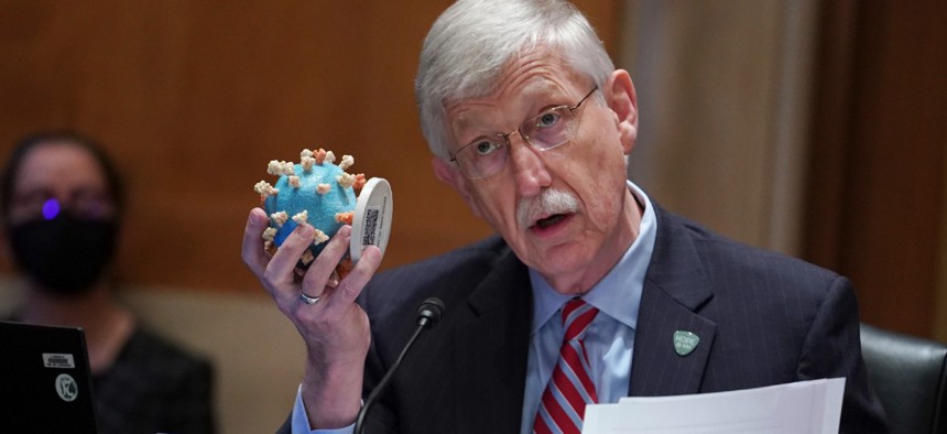 NIH Director Dr. Francis Collins holds up a model of the coronavirus as he testifies before a Senate Appropriations subcommittee in May. 