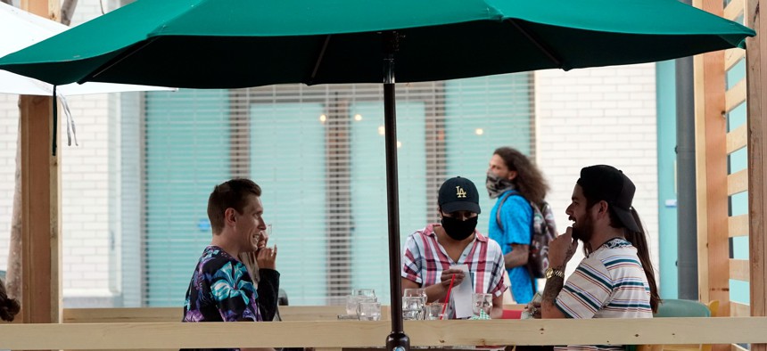 A server tends to customers in an outdoor dining area amid the COVID-19 pandemic on The Promenade on June 9 in Santa Monica, Calif.