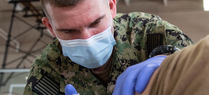 Hospital Corpsman 3rd Class Joseph Casassa, assigned to USS Gerald R. Ford’s dental department, administers a COVID-19 vaccine at the McCormick Gym onboard Naval Station Norfolk in April 2021. 