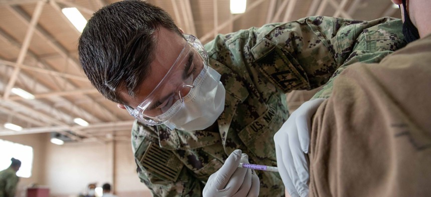Hospital Corpsman 3rd Class Robert Moore, assigned to USS George W. Bush  medical department, administers a COVID-19 vaccine at the McCormick Gym onboard Naval Station Norfolk in April.