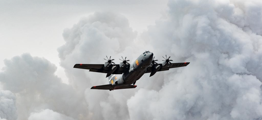 An Air National Guard C-130 flies over the plumes of smoke after dropping retardant on the Beckwourth Complex Fire, July 9, 2021 near Frenchman Lake in N. California. 