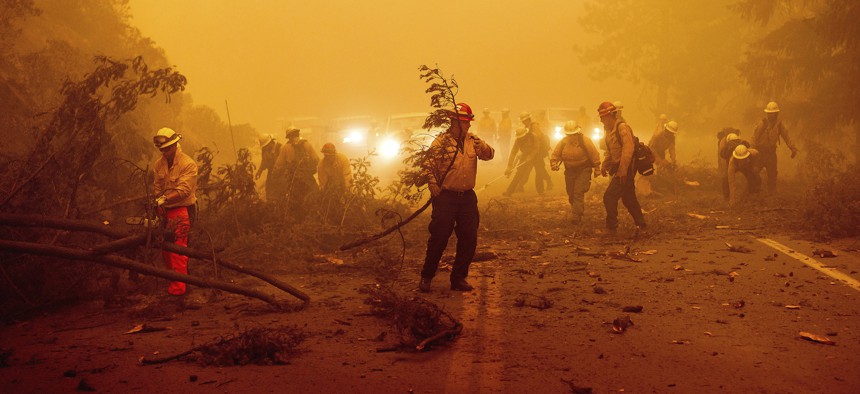 Firefighters battling the Dixie Fire clear Highway 89 in Plumas County, California, last week. An infrastructure bill passed by the U.S. Senate would lay the groundwork for raising firefighter pay.