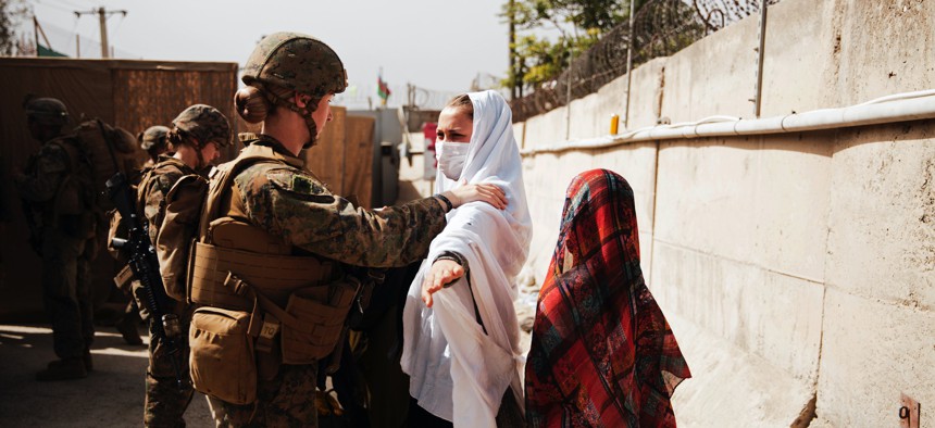 A U.S. Marine checks two civilians during processing through an Evacuee Control Checkpoint during an evacuation at Hamid Karzai International Airport, in Kabul, Afghanistan, on Aug. 18, 2021.