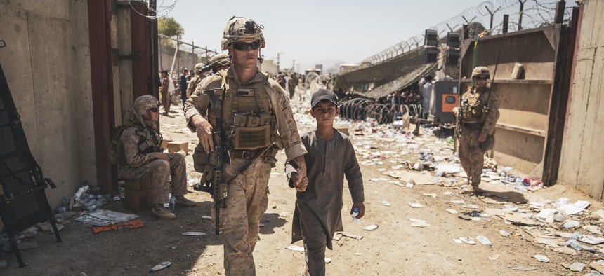 A U.S. Marine with the Special Purpose Marine Air-Ground Task Force-Crisis Response-Central Command escorts a child to his family during an evacuation at Hamid Karzai International Airport, Kabul, Afghanistan, Aug. 24. 