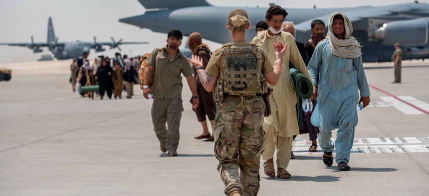 A member from the 379th Air Expeditionary Wing guides qualified evacuees debarking a C-17 Globemaster lll on Aug. 23 at Al Udeid Air Base, Qatar. 