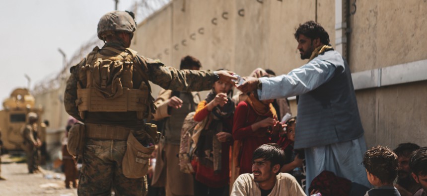 A Marine with the 24th Marine Expeditionary unit (MEU) passes out water to evacuees during an evacuation at Hamid Karzai International Airport, Kabul, Afghanistan, Aug. 22.