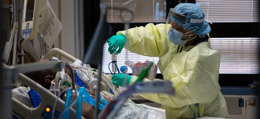 A nurse puts fluids into the feeding tube of a COVID-19 patient at the Medical Intensive Care Unit floor at the Veterans Affairs Medical Center in New York City in April 2020. 