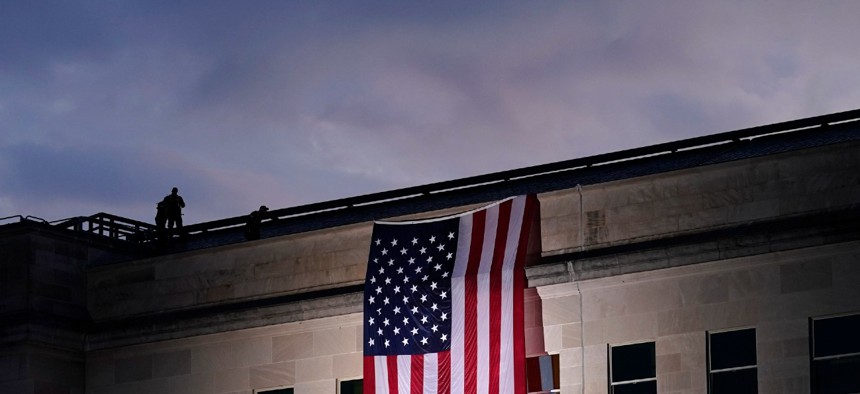A plane takes off from Washington Reagan National Airport on Sept. 11, 2020, as a large American flag is unfurled at the Pentagon ahead of ceremonies at the National 9/11 Pentagon Memorial to honor the people killed in the 2001 terrorist attack. 