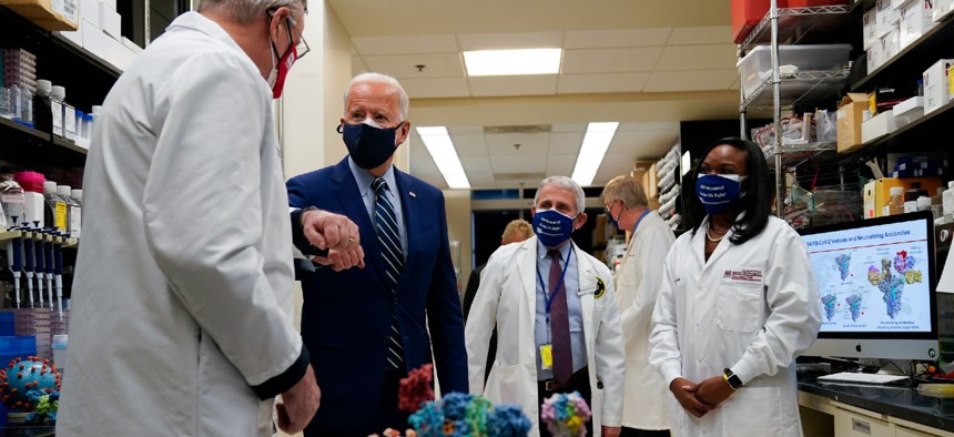 President Joe Biden greets Dr. Barney Graham, left, as he visits the Viral Pathogenesis Laboratory at the National Institutes of Health in February. Graham and Dr. Kizzmekia Corbett, shown at right, were recognized as federal employees of the year. 