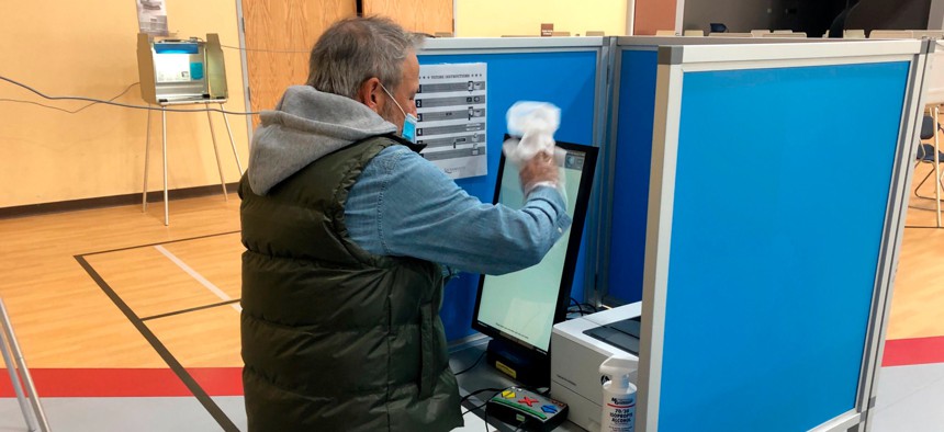 Paul Bergman cleans a voting machine at the Oak Park Community Center on Monday, Oct. 27, 2020, in Sacramento, California. 