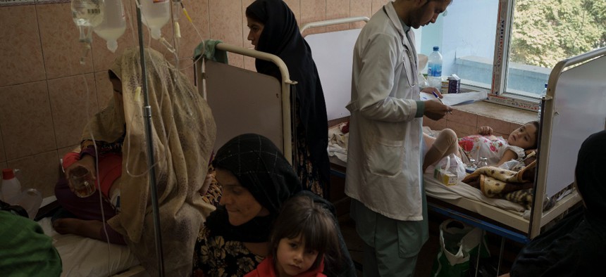 A doctor checks on girl as other parents and patients sit in a crowded room at the Indira Gandhi Children's Hospital in Kabul, Afghanistan, Tuesday, Oct. 5, 2021.