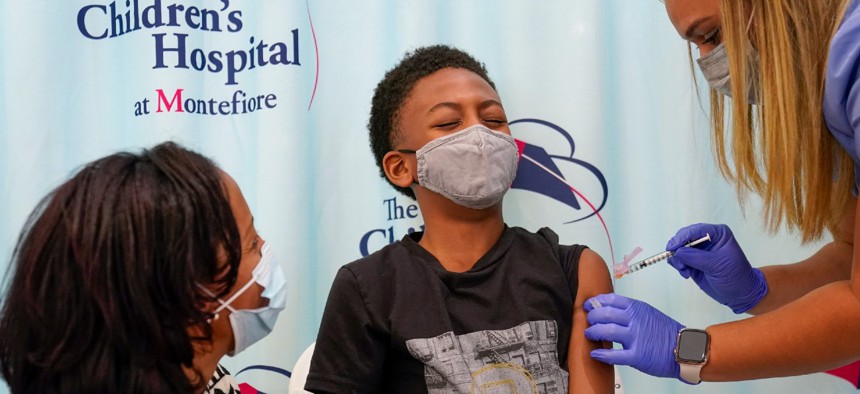 Dr. Rhonda Achonolu comforts her son Kenechi, 9, as he is inoculated Wednesday with first dose of the Pfizer-BioNTech COVID-19 vaccine for children five to 12 years, at The Children's Hospital at Montefiore, in the Bronx borough of New York. 