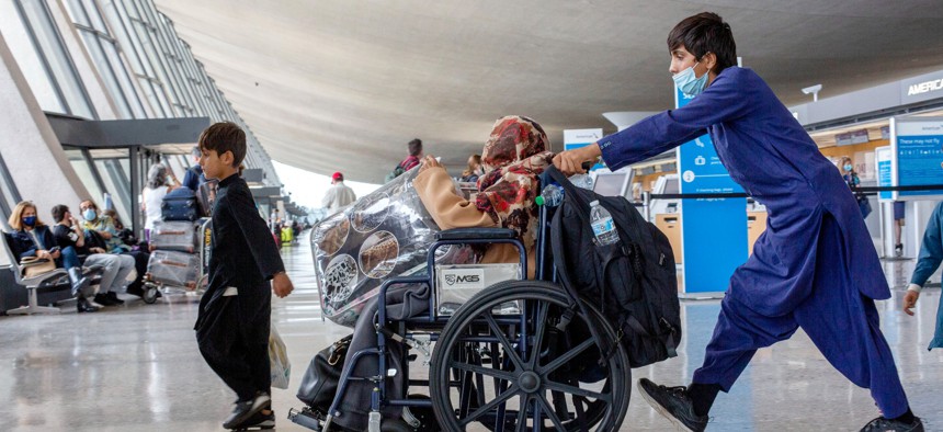 Children evacuated from Kabul, Afghanistan, pushes a wheel chair with a woman at Washington Dulles International Airport, in Chantilly, Va., on Wednesday, Sep. 1, 2021. 