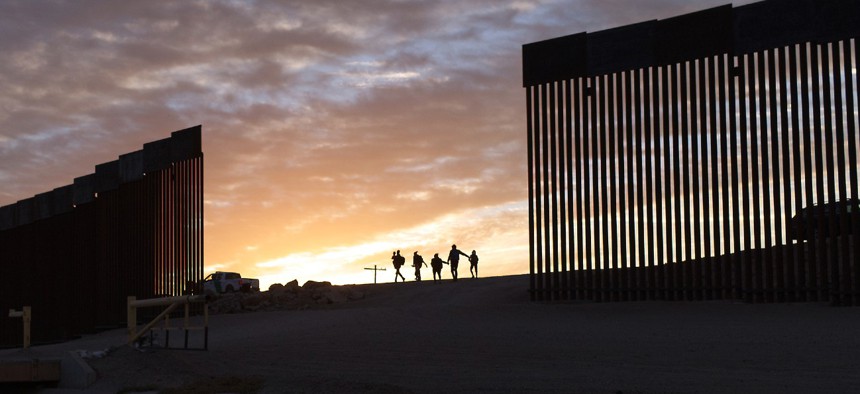 A pair of migrant families from Brazil passes through a gap in the border wall to reach the United States after crossing from Mexico in Yuma, Ariz., in June 2021 to seek asylum. 
